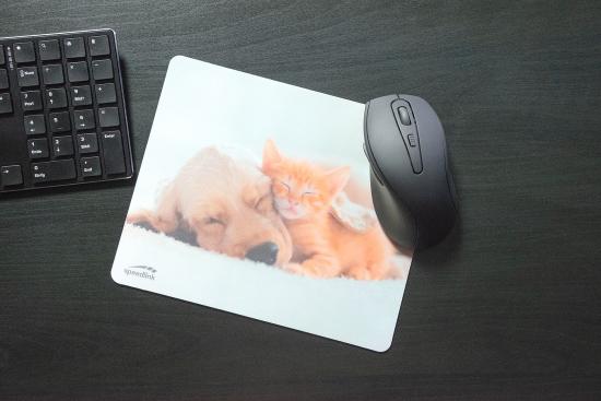 Ein Mauspad mit dem Bild eines schlafenden Welpen und Kätzchens, daneben eine kabellose Maus und eine Tastatur