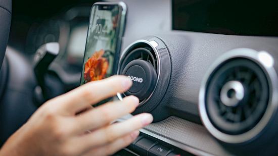 Nahaufnahme einer Hand, die ein Smartphone in eine Auto-Lüftungs-Halterung einsetzt