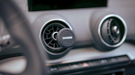 Nahaufnahme eines Ooono Geräts in einem Auto-Lüftungsschlitz, kleines rundes Gerät zur Verkehrsüberwachung.