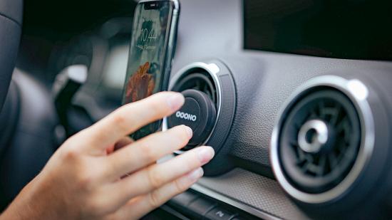 Hand befestigt ein Smartphone an einer magnetischen Autohalterung in den Lüftungsschlitzen