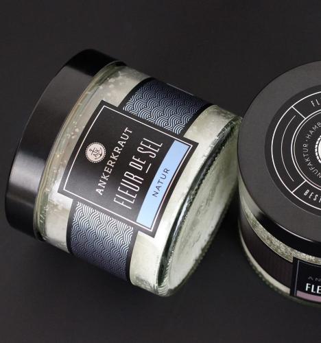 Zwei Gläser Ankerkraut Fleur de Sel auf schwarzem Hintergrund