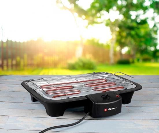 Elektrischer Tischgrill auf Holztisch im Garten