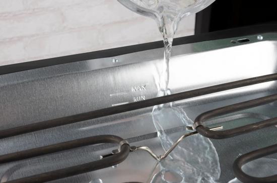 Nahaufnahme der Wasserbefüllung eines Edelstahl-Dampfbügeleisens mit Maximal- und Minimal-Markierungen