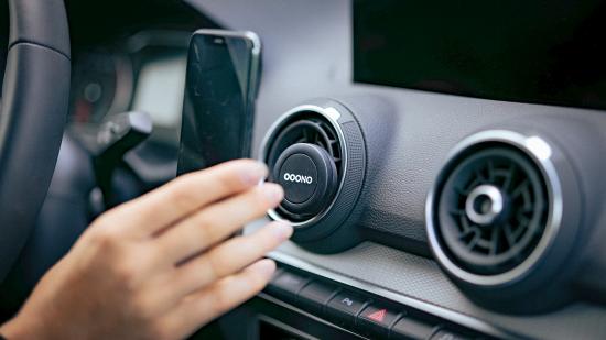 Nahaufnahme einer Hand, die ein Smartphone in eine Lüftungshalterung im Auto einsetzt