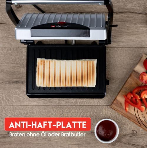 Elektrischer Kontaktgrill mit Anti-Haft-Platte, Sandwich auf Grill, Paprika und Ketchup im Hintergrund