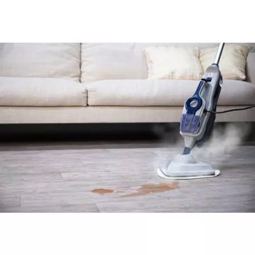 Ein Dampfreiniger reinigt einen Laminatboden vor einem Sofa und entfernt einen Fleck.