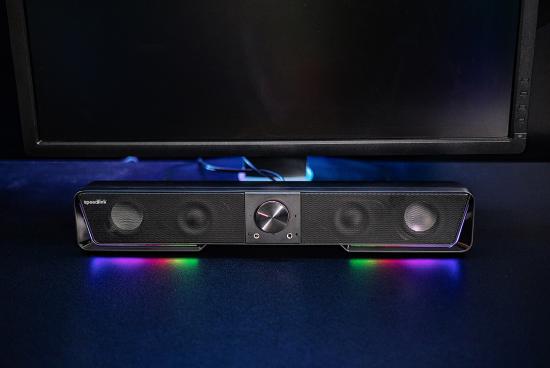 Schwarze Soundbar mit bunten LED-Lichtern unter einem Monitor auf einem Schreibtisch